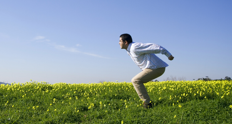 man preparing to jump up into the air in a yellow flower field