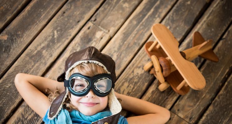 child looking upward with wooden plan next to them