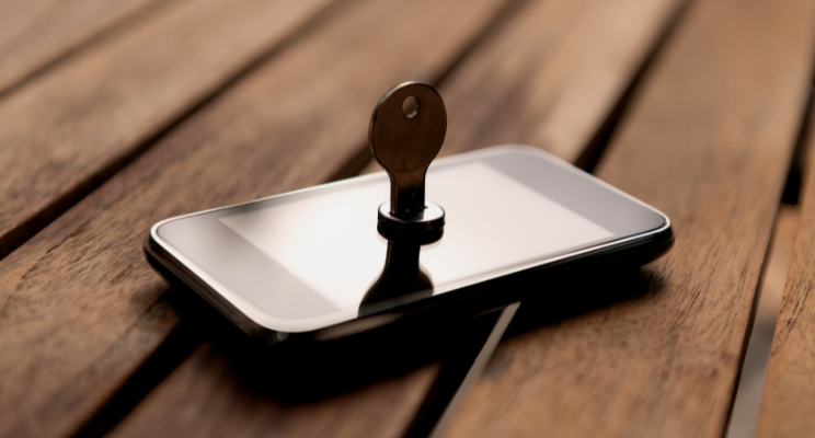 smartphone on wooden table with key inserted into the screen