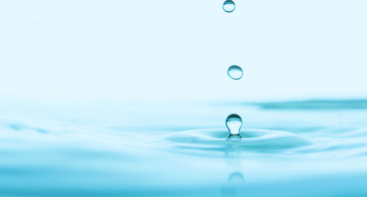 three drops of water falling into larger body of water up close