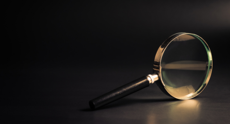 golden magnifying glass against black background