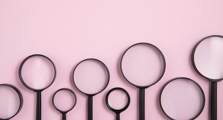 alternating size black magnifying glasses against pink background