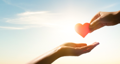 two hands exchanging a animated red heart with a sunset in the background